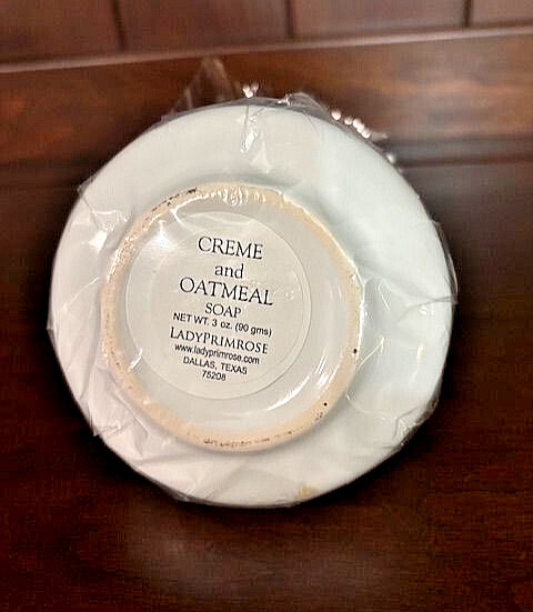 LADY PRIMROSE “CREME AND OATMEAL” SOAPS ON A SMALL WHITE PLATE, TWO 3 OZ BARS